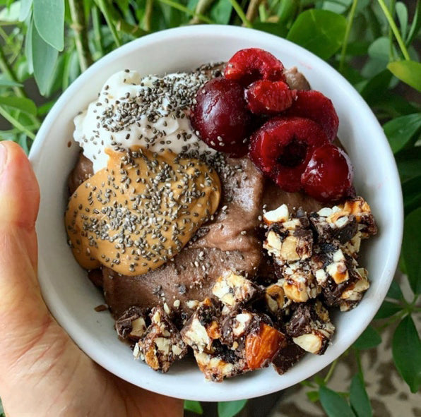 Bowl of Chocolate Super Greens smoothie with fruits and nuts on top