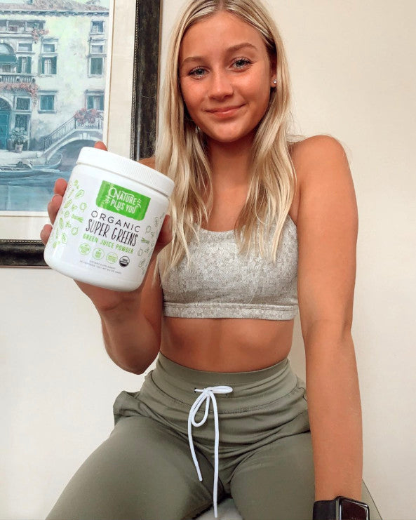 Young woman holding a bottle of Super Greens