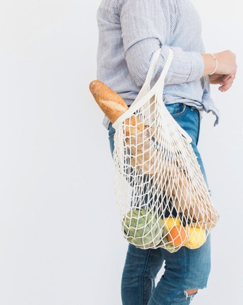 Woman holding a reusable grocery bag with produce inside
